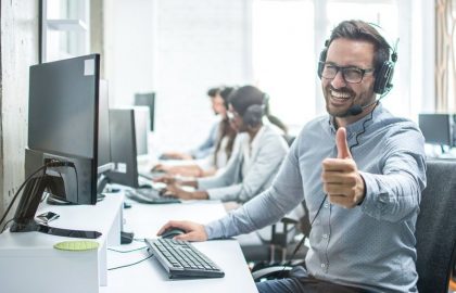 Comp-Cheerful-male-customer-service-operator-showing-thumbs-up-in-office.-art2